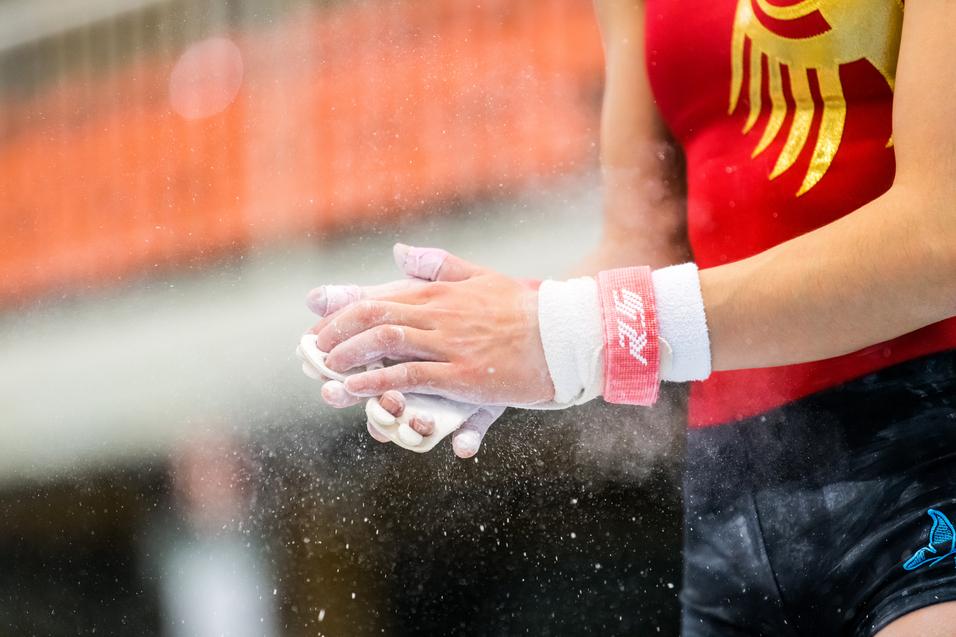 Nahaufnahme von Händen eines Turners mit Chalk, die vor einem Wettkampf im Gymnastik bereitgemacht werden.